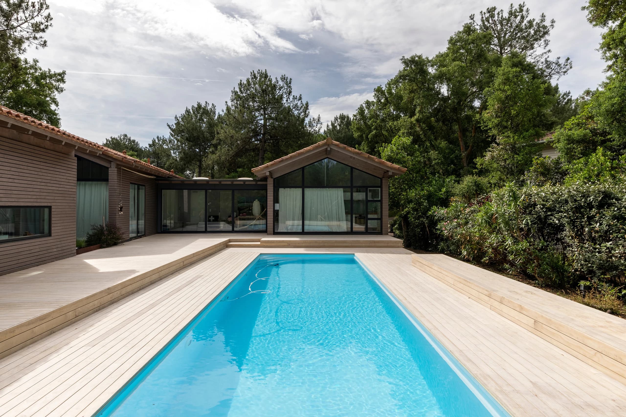 Villa et piscine entourées d’une grande terrasse en bois Accoya naturel