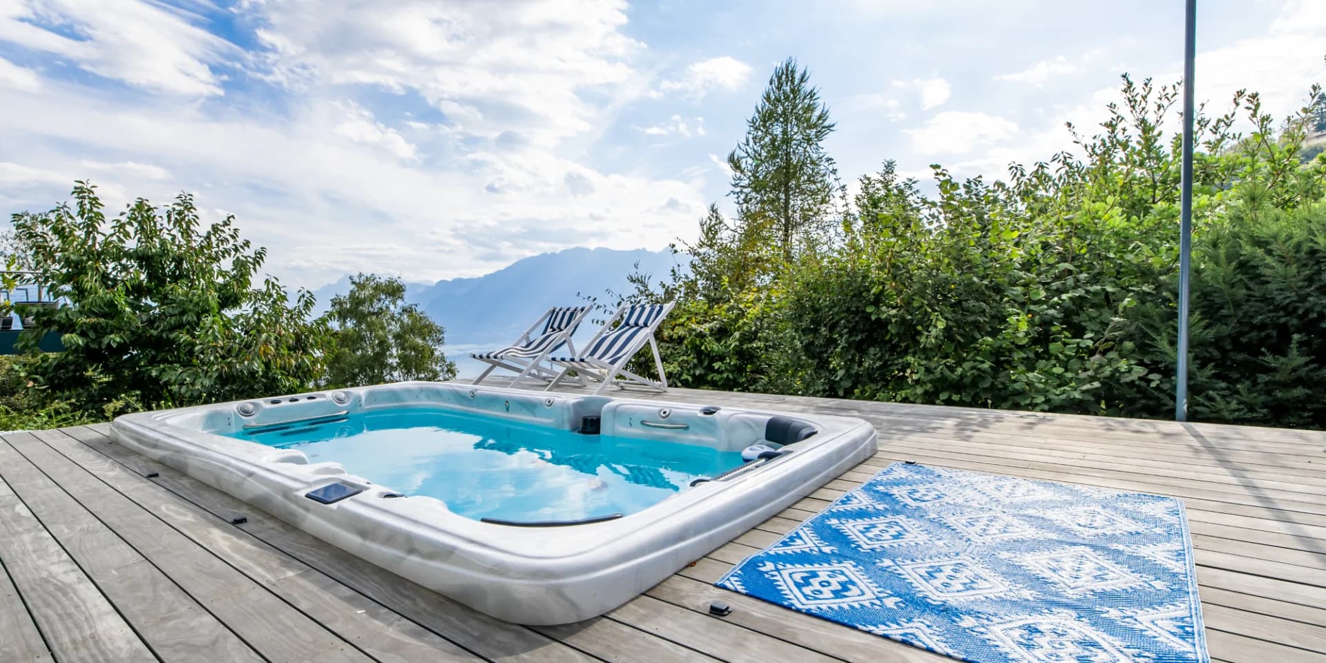 Spa encastré dans un deck en bois gris argenté, deux transats face au panorama